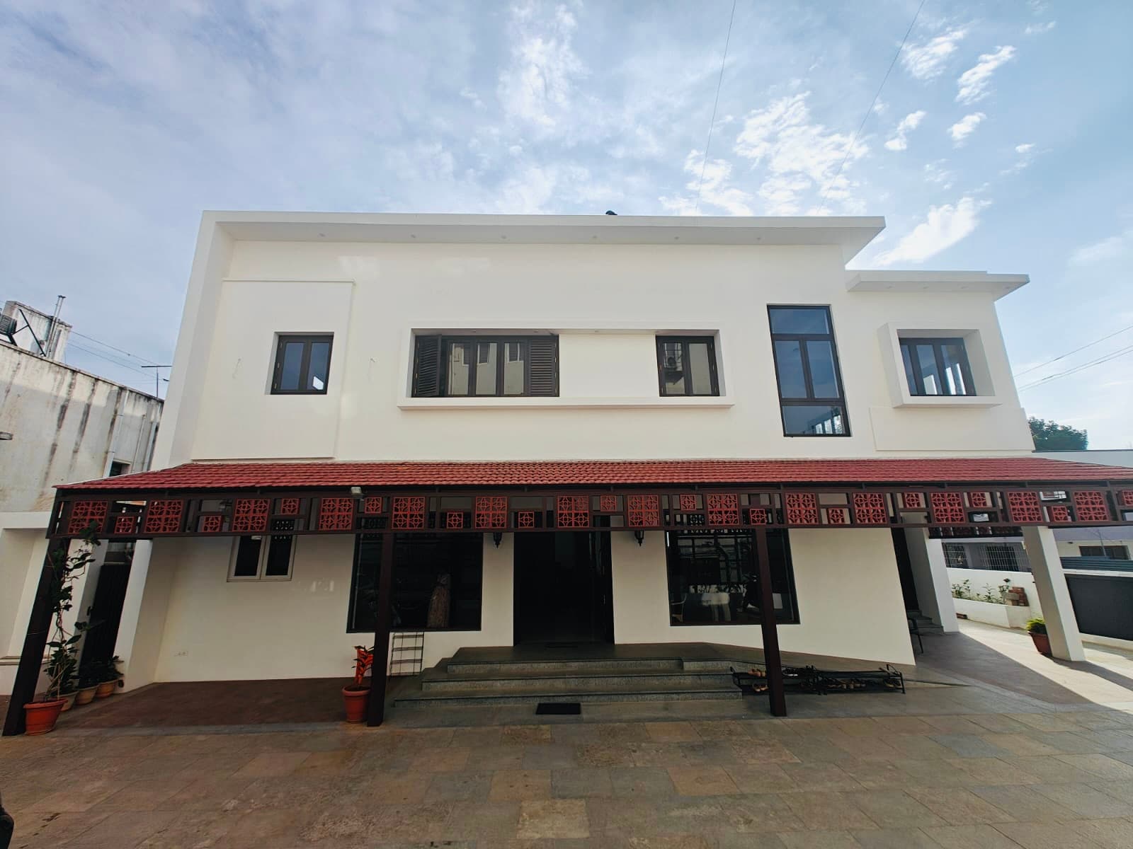 The clinic front elevation: white walls, a red-tiled veranda and terracotta jaali screens