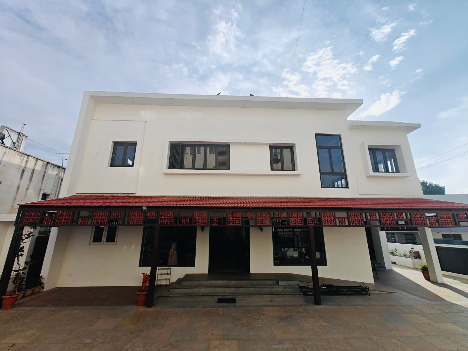 The clinic seen head-on: two white storeys over a red-tiled veranda edged with terracotta jaali