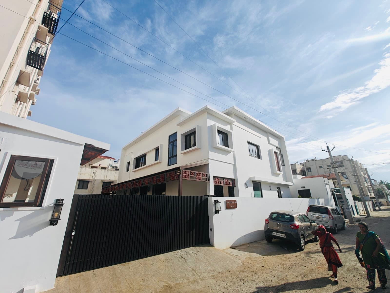 The clinic from the street corner, neighbours walking past the compound wall