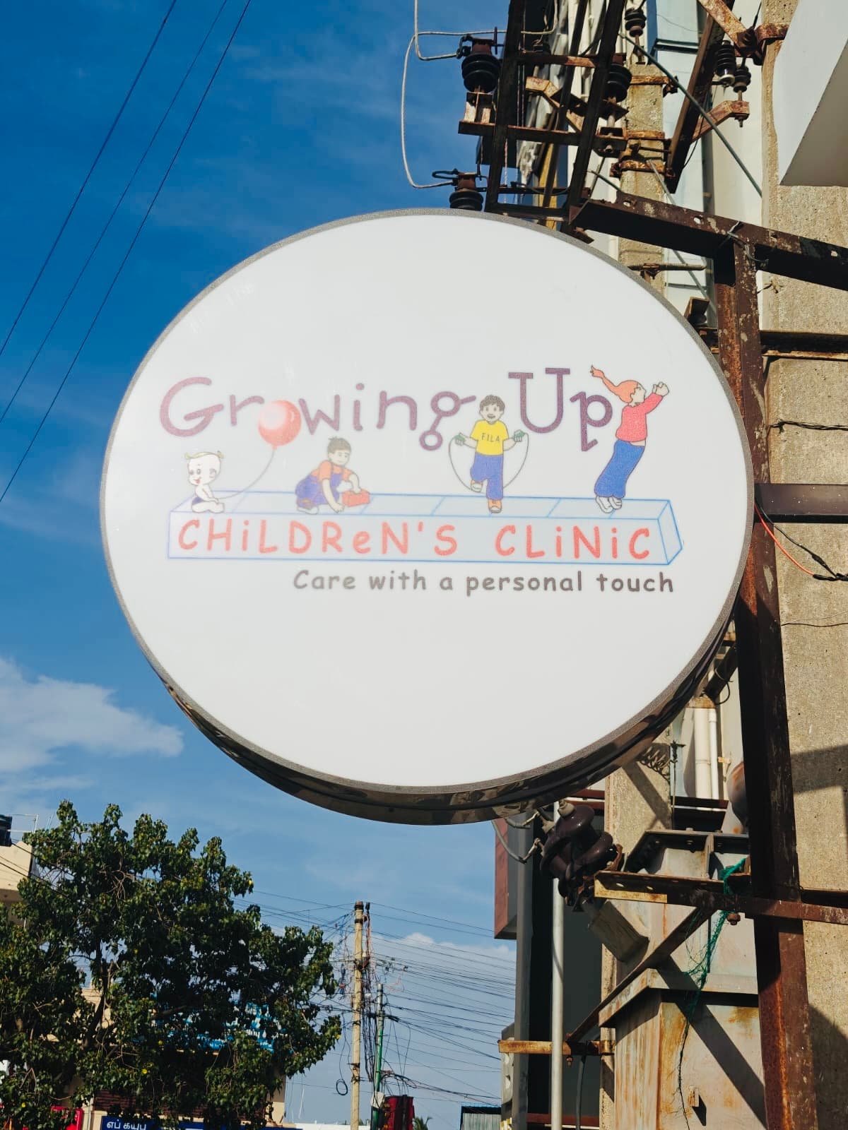 The round hanging sign: Growing Up Children's Clinic, care with a personal touch