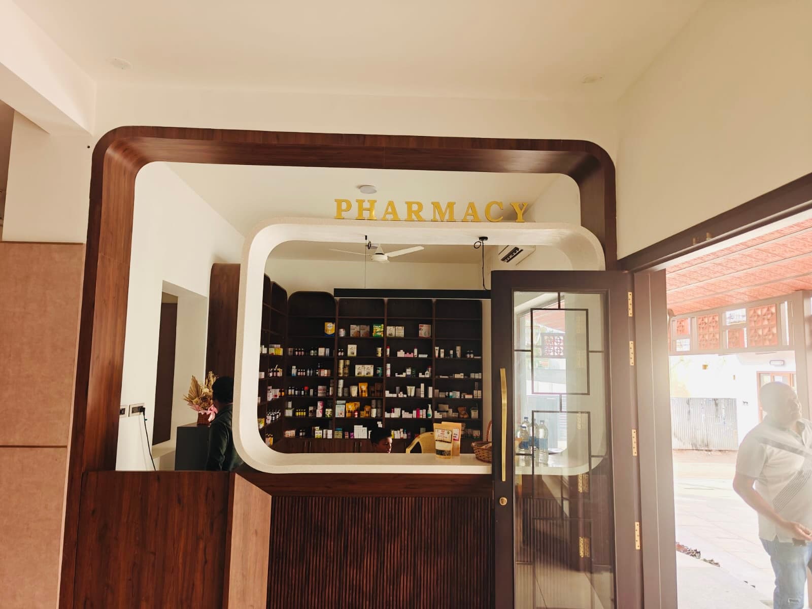 The in-house pharmacy behind a rounded walnut arch with brass PHARMACY lettering