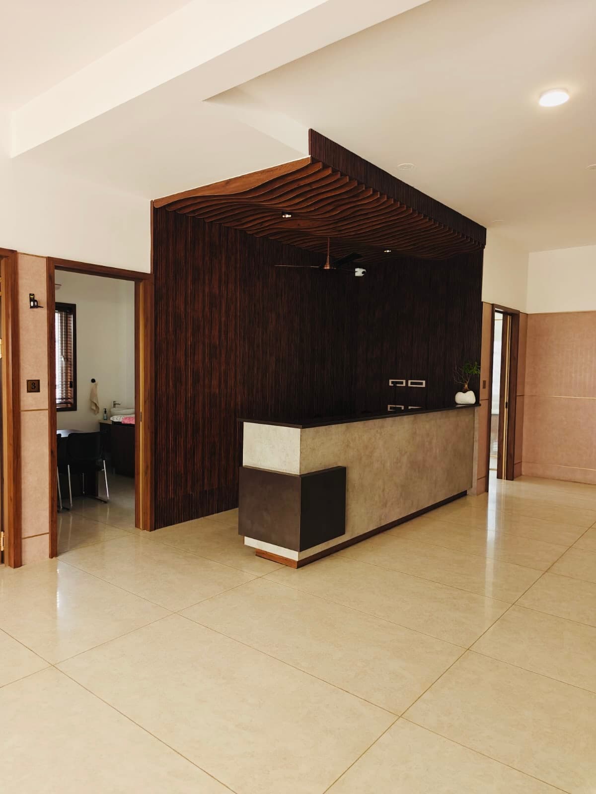 The reception desk in front of a fluted teak wall with a sculpted wave ceiling above