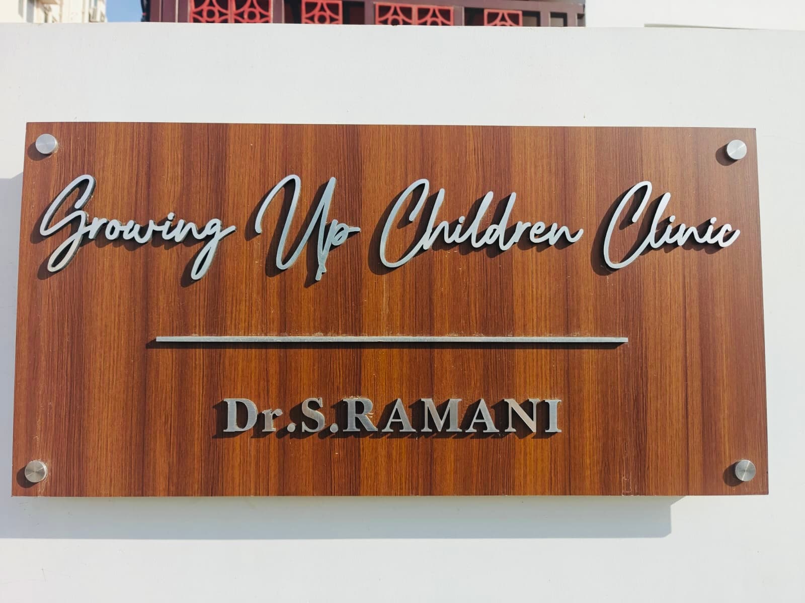 The clinic nameplate in teak and steel: Growing Up Children Clinic, Dr. S. Ramani
